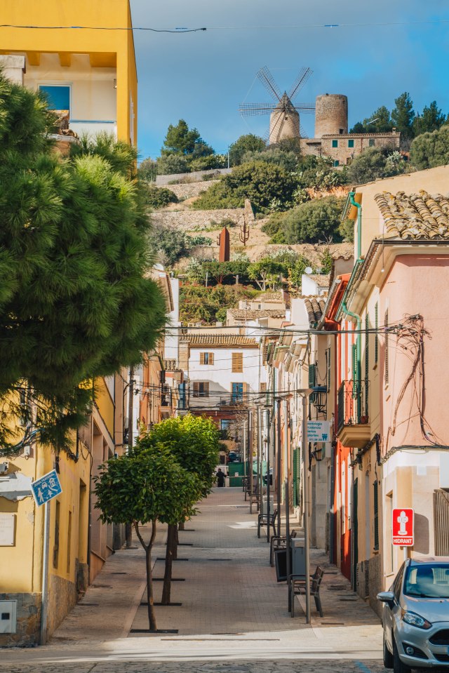 Street scene in Balearics with a windmill on a hill in the background.