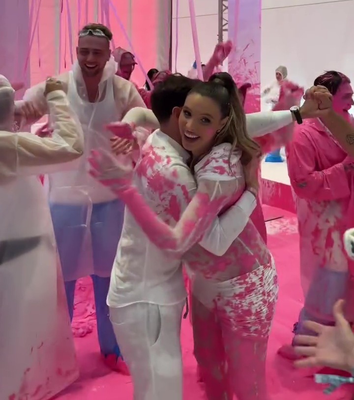 Couple embracing at a pink gender reveal party.