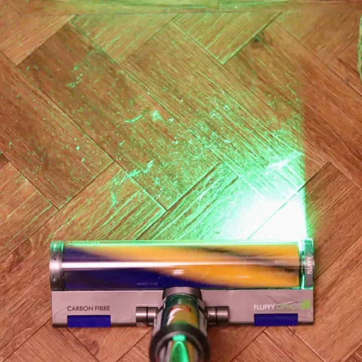 Dyson V15 Detect vacuum cleaner cleaning a wood floor.