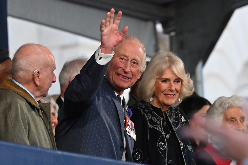 King Charles III and Camilla, Queen Consort, waving at a VE Day anniversary concert.