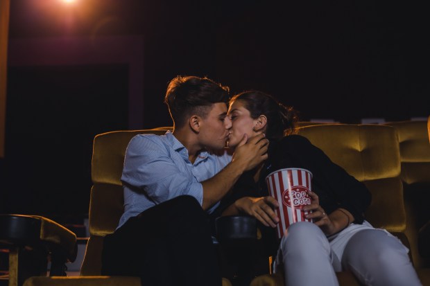 Couple kissing while watching a movie at the cinema.