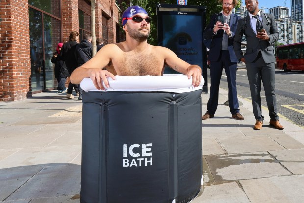 Man taking an ice bath at a bus stop.