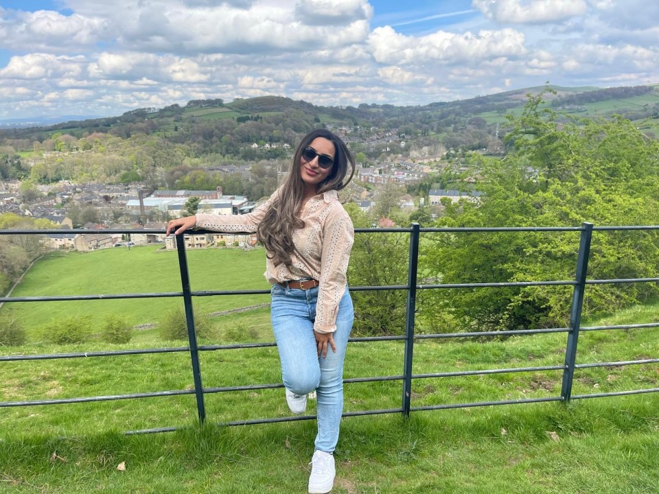 Woman standing by a fence overlooking a town.
