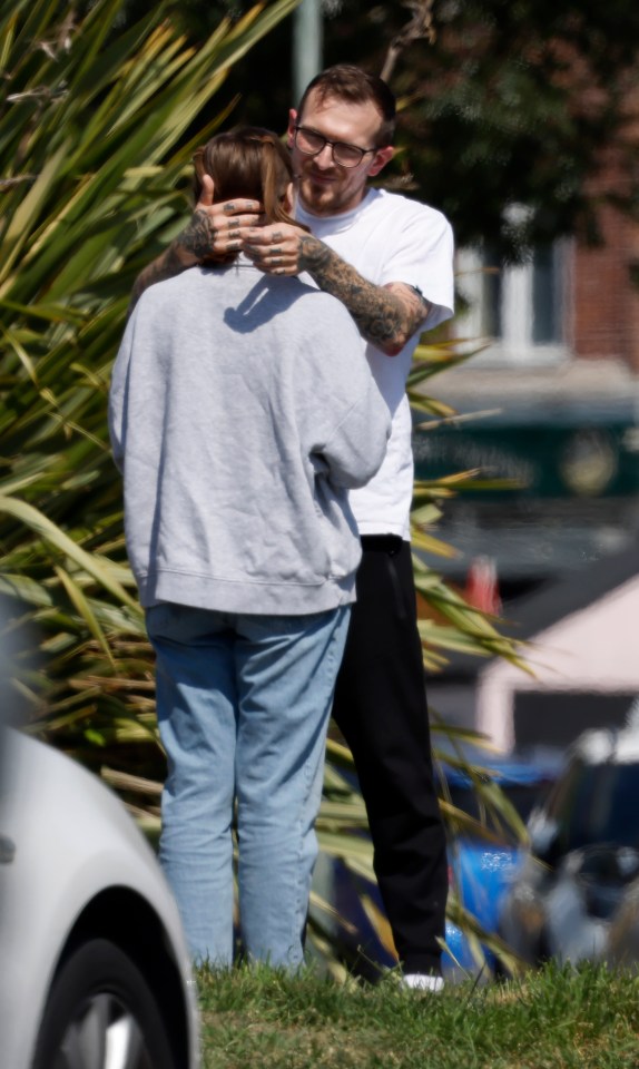 A man with tattoos embracing a woman.