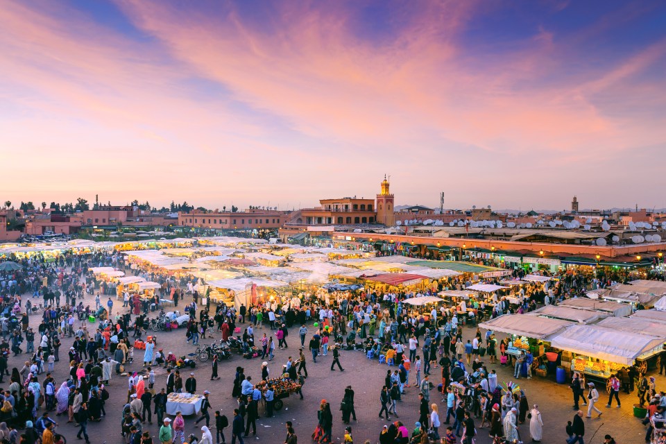 Djemaa el-Fna square in Marrakech at dusk, crowded with people and market stalls.