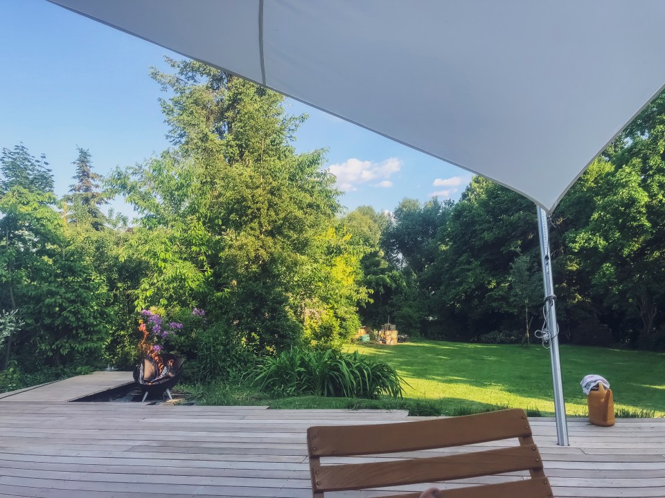 View of a garden from a deck under a shade sail.