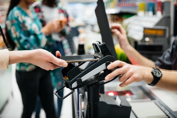 Close-up of contactless payment with smartphone at a supermarket checkout.