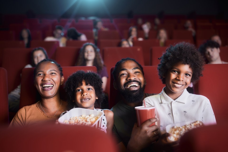 Black family enjoying a movie at the cinema.