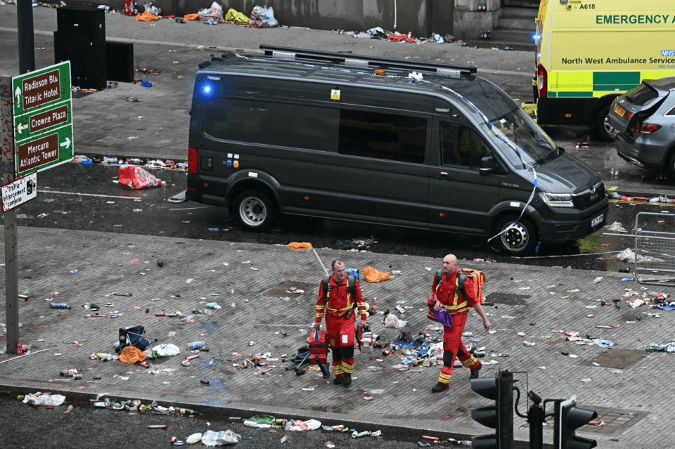 Paramedics walking amidst litter and emergency vehicles.