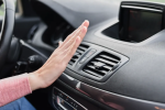 Hand testing car air vent temperature.