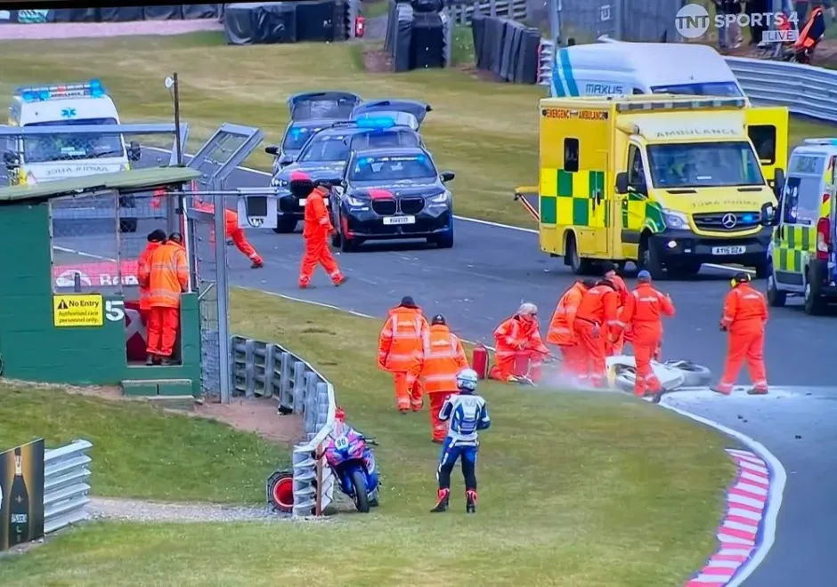 Emergency responders attending to a motorcycle accident on a racetrack.