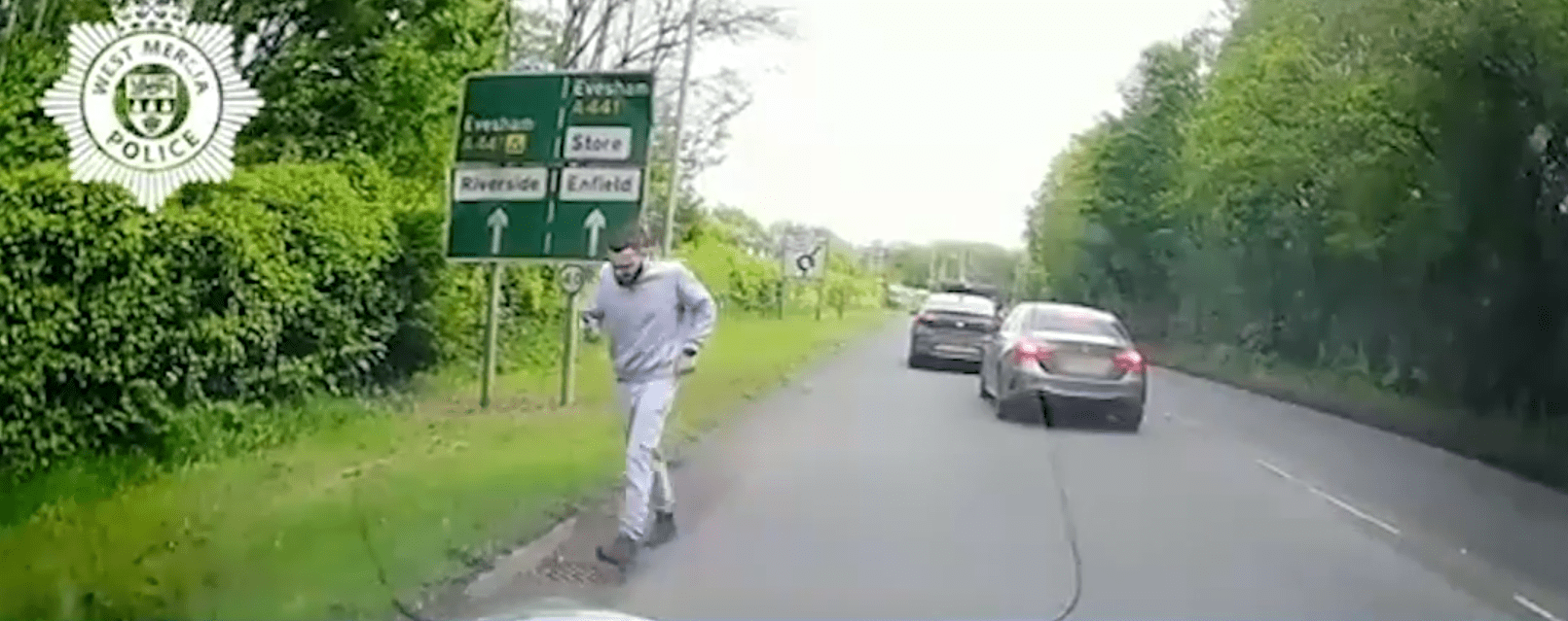 Dashcam footage of a man walking along a road after a car crash.