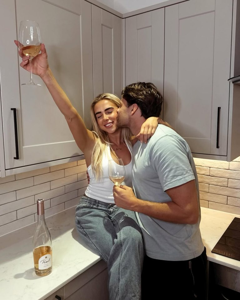Couple embracing in a kitchen, drinking wine.