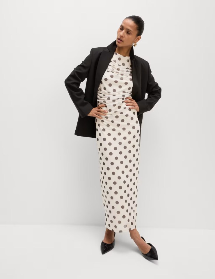 Woman in polka dot dress and black blazer.