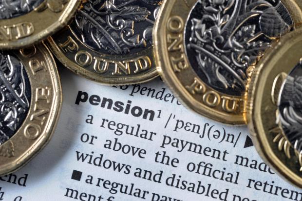 One pound coins on a dictionary page showing the definition of "pension".