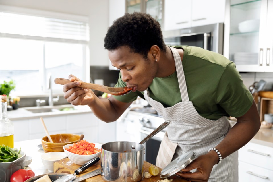 A man tasting sauce while cooking.