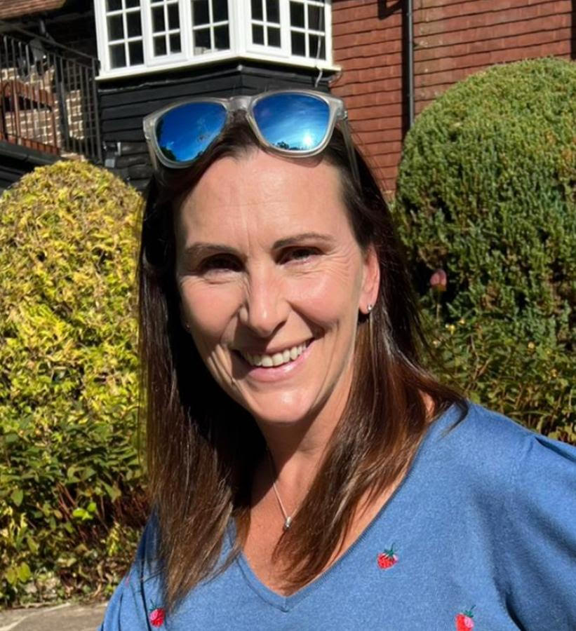 Woman in blue shirt with sunglasses on her head.