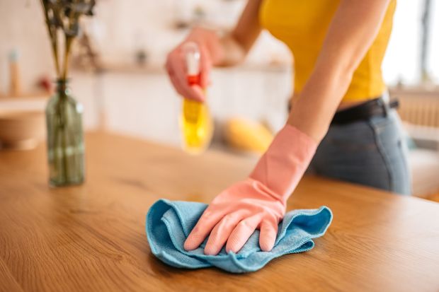 An image collage containing 1 images, Image 1 shows Woman cleaning a wooden table with a spray bottle and cloth