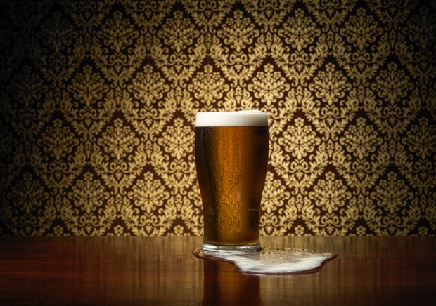 Pint of beer overflowing onto a pub table.