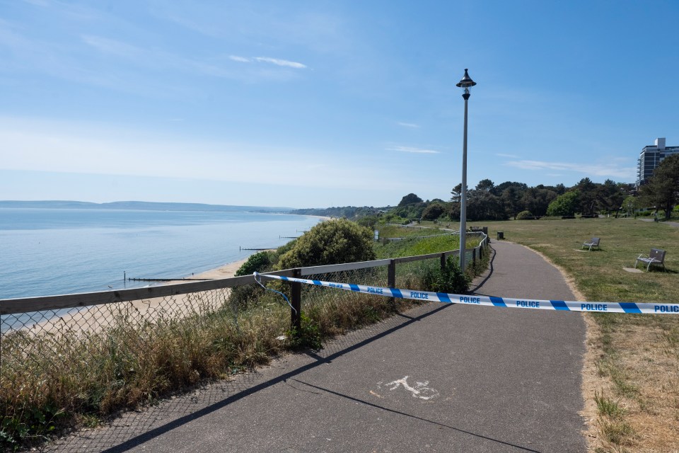 Police tape across a path overlooking a beach.