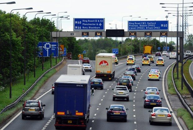 Police escorting a slow-moving convoy of vehicles on a highway.