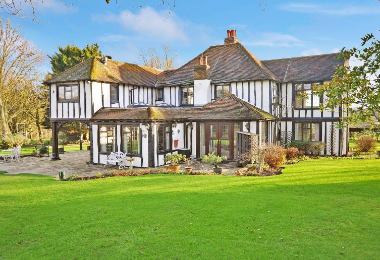 Large black and white Tudor-style house with a sunroom.