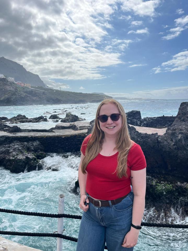 Woman in red shirt and jeans by the ocean in Tenerife.