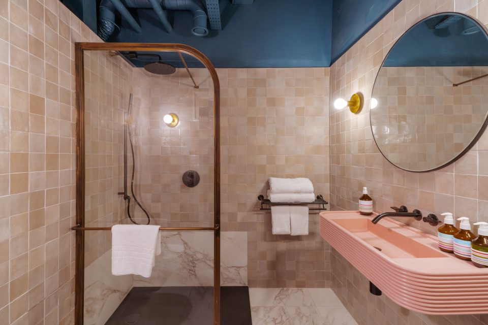 Hotel bathroom with pink sink and walk-in shower.