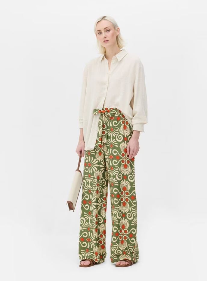 Woman wearing cream shirt and patterned wide-leg trousers.
