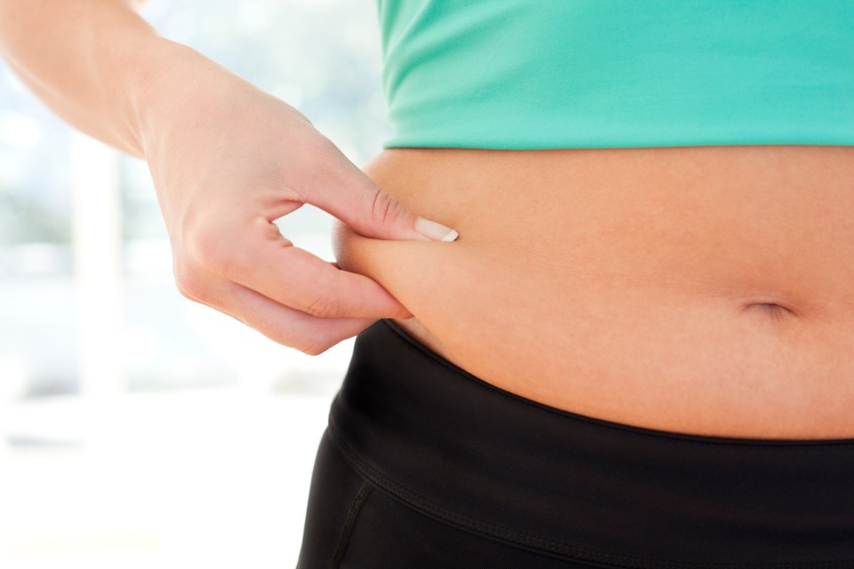 Woman pinching excess fat on her waist.