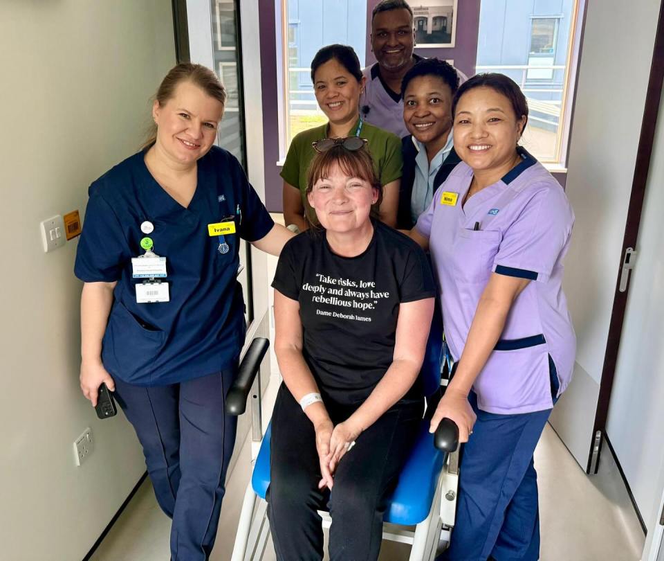 A woman in a wheelchair surrounded by hospital staff.