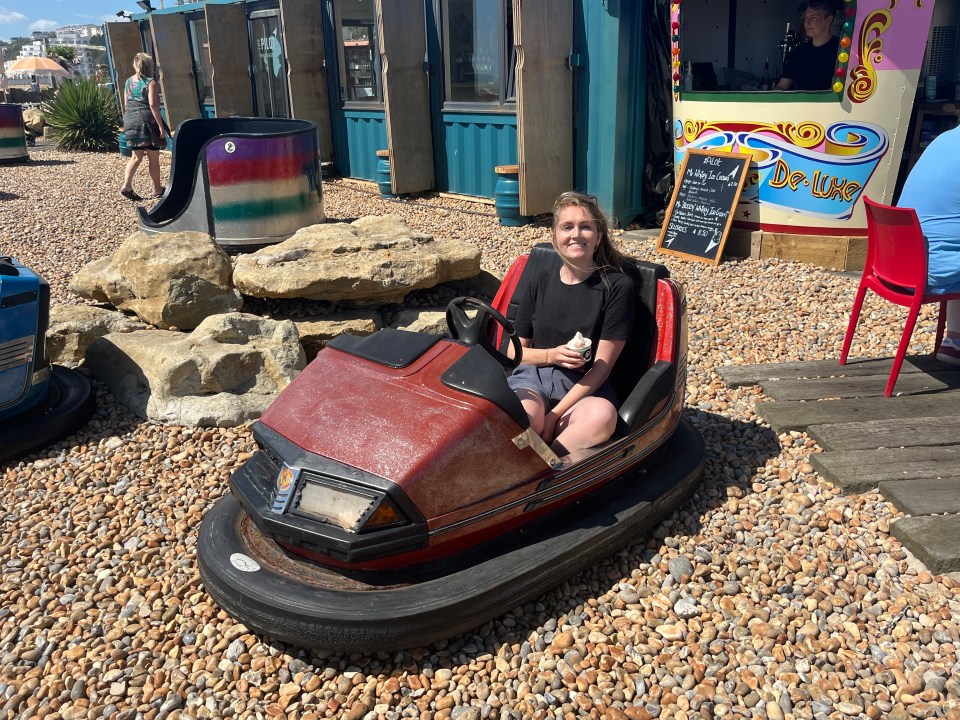 Woman sitting in a bumper car eating ice cream.