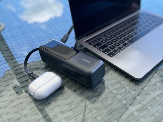 Anker laptop charger, AirPods case, and laptop on a table.