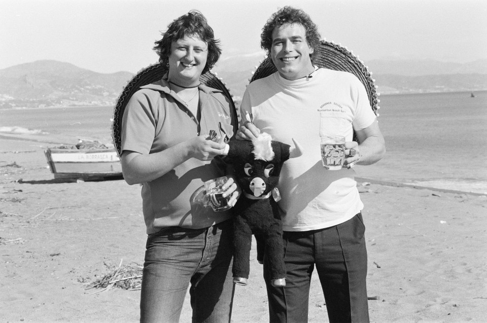 Black and white photo of Eric Bristow and Bobby George on a beach in Spain.