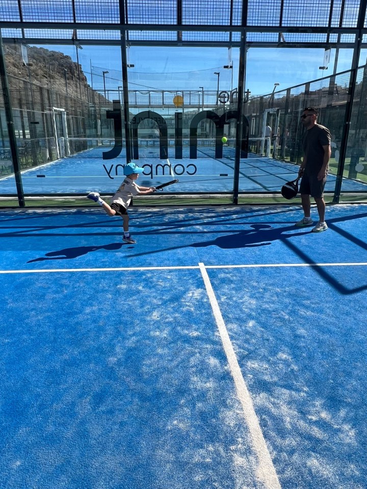 A child and an adult playing paddle tennis.