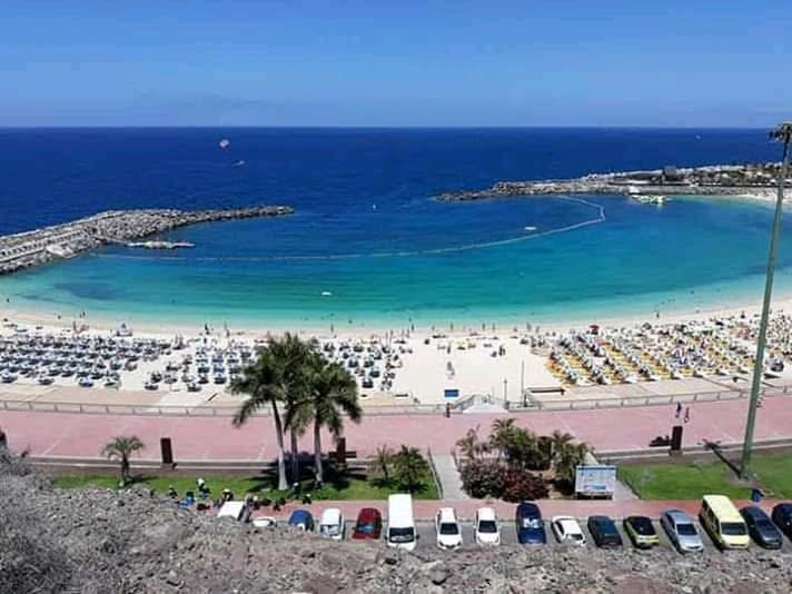 Aerial view of a beach with turquoise water and many umbrellas.