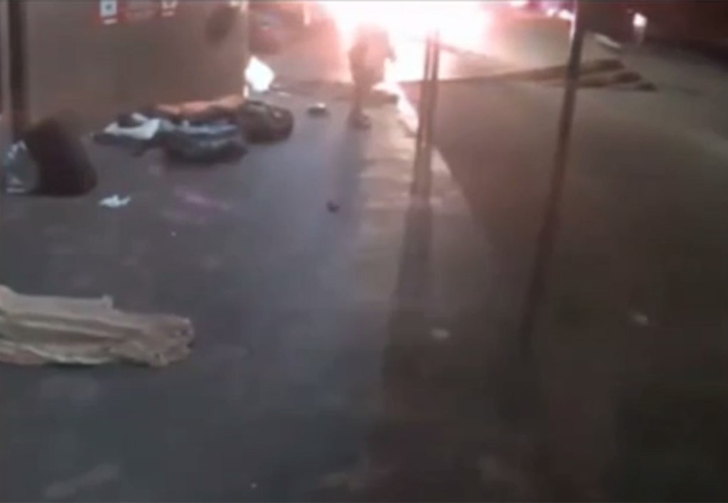In a massive flash, the attacker chucks the Molotov Cocktail at the group of sleeping people