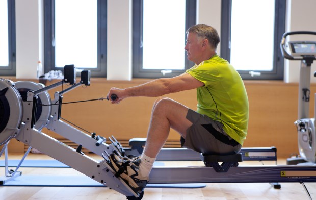 Senior man exercising on rowing machine in gym