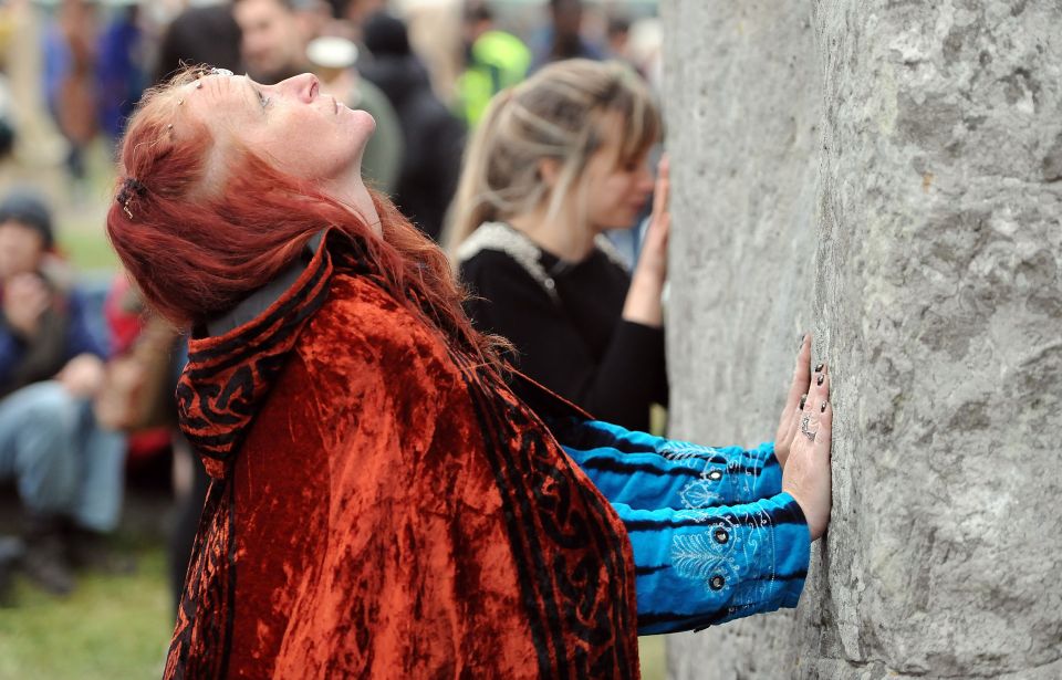 Women touch the the stones at Stonehenge in Wiltshire