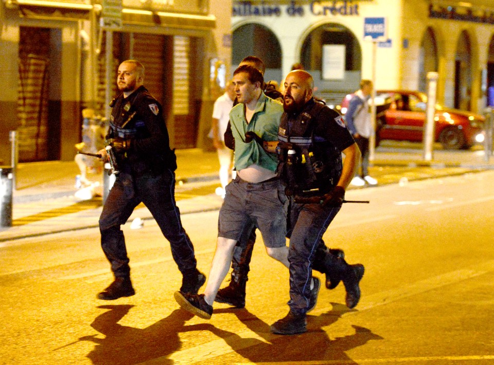 An England fan is marched away from the scene by police following violence in Marseille