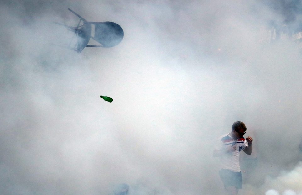 One England fan cowers amid the smoke as a chair is hurled through the air