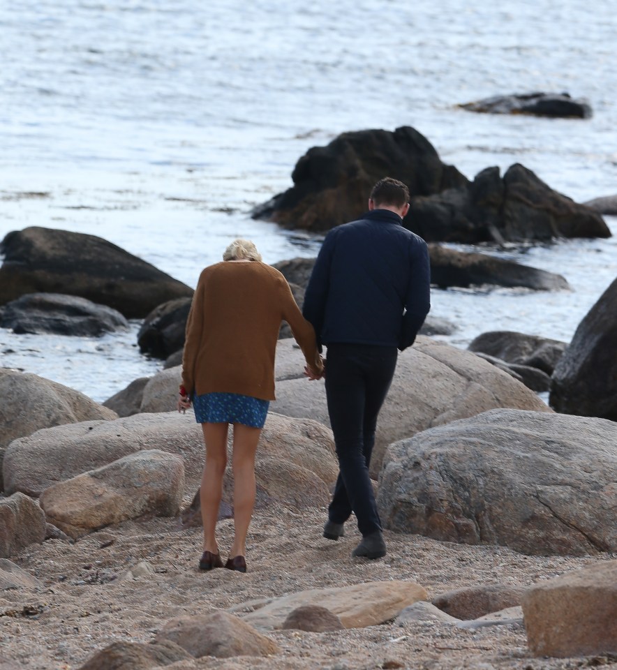Taylor Swift and new love Tom Hiddlestone walk hand in hand along the beach and find a quiet romantic spot on the rocks 