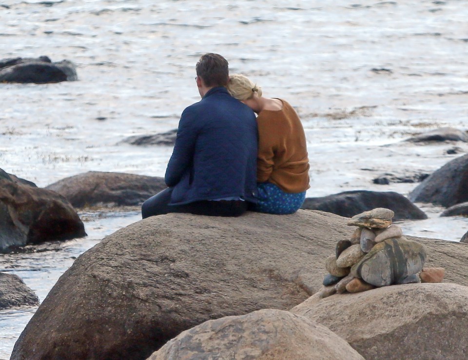 Taylor Swift leans her head on Tom Hiddlestone's shoulder as they stare out to sea during a romantic moment on the rocks of one of her favourite beaches