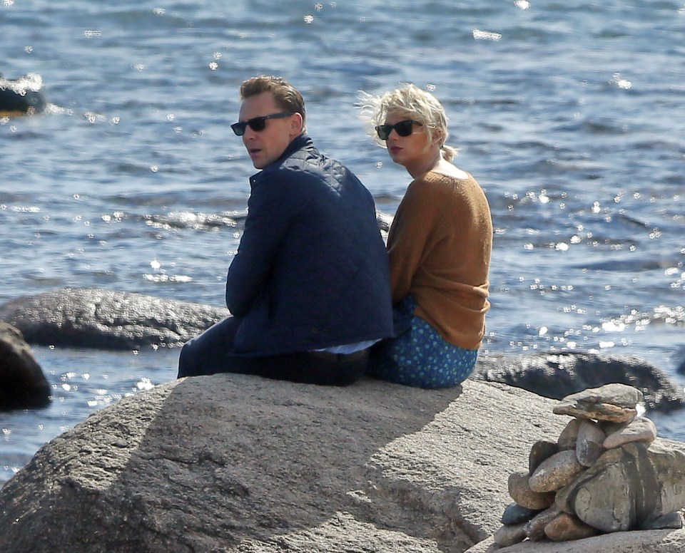 Something catches the lover's eyes as they stare out to sea while enjoying a romantic moment on the rocks 