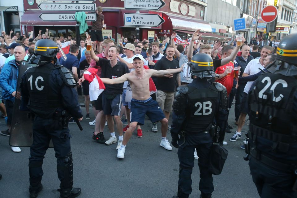 Riot police monitor England fans outside the train station in Lille
