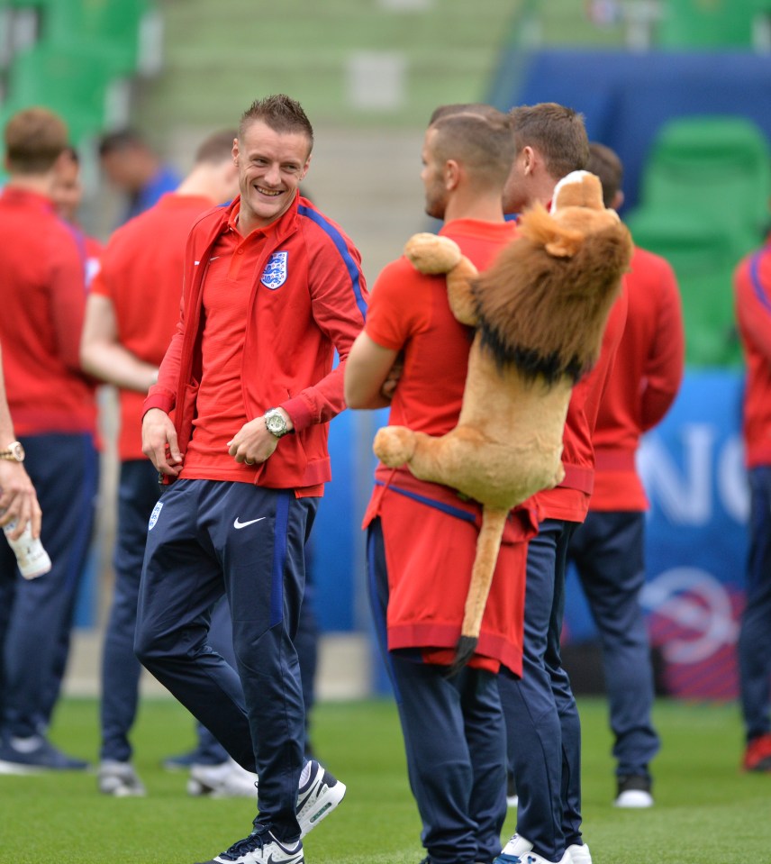 Jamie Vardy laughs at Jack Wilshere as the midfielder is given Leo the Lion to carry