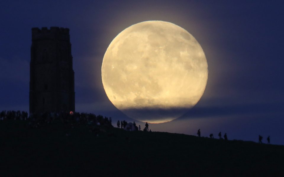 A full moon rises behind Glastonbury Tor as people gathered to celebrate the summer solstice on June 20