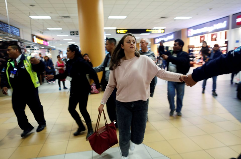 Melissa Reid walks next to an immigration officer before boarding a flight at Lima's airport in Callao