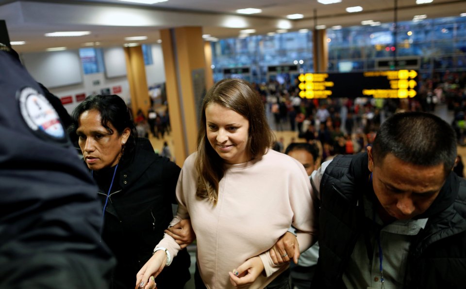 Melissa Reid walks next to immigration officers before boarding a flight at Lima's airport in Callao