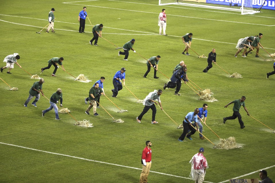 Workers remove water from the field, during a rain delay before the second half 
